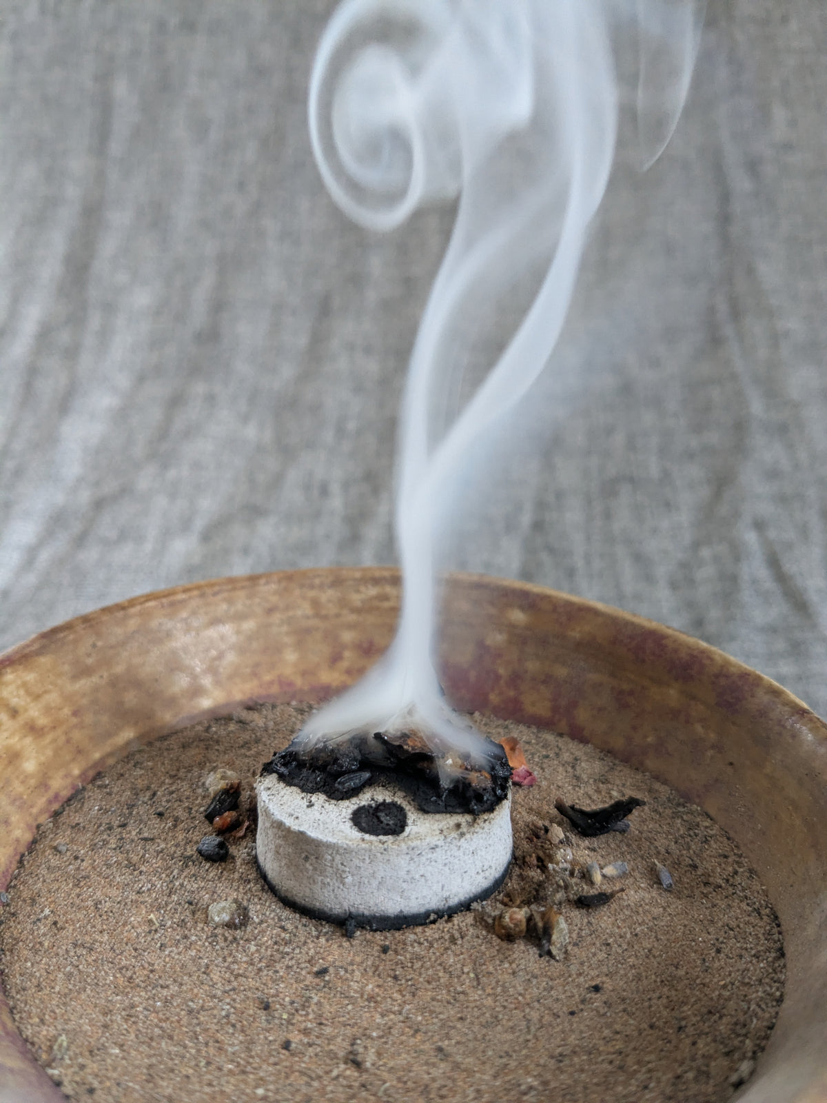 Räucherschale aus Keramik mit glimmender Kräutermischung und aufsteigendem Rauch.